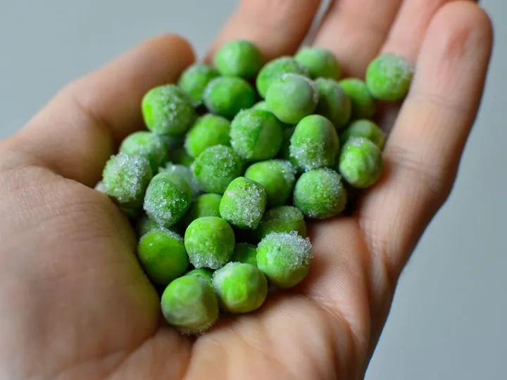Hand holding frozen green peas