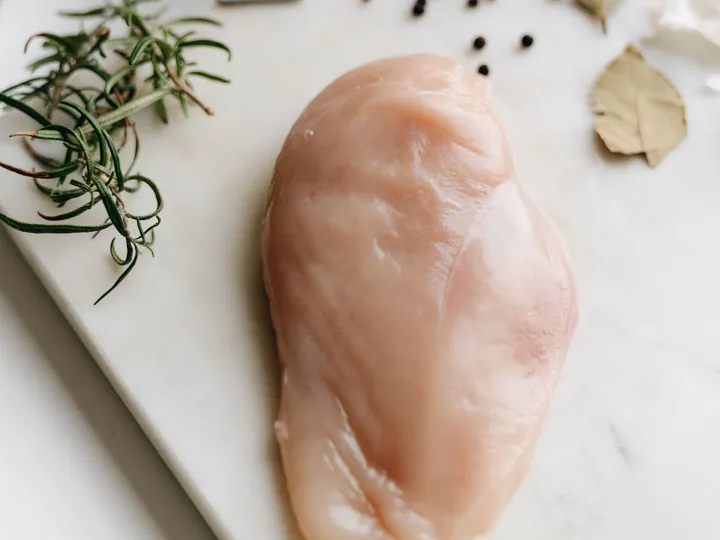 Raw chicken breast with herbs on a work surface