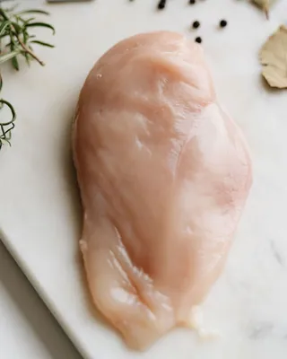 Raw chicken breast with herbs on a work surface